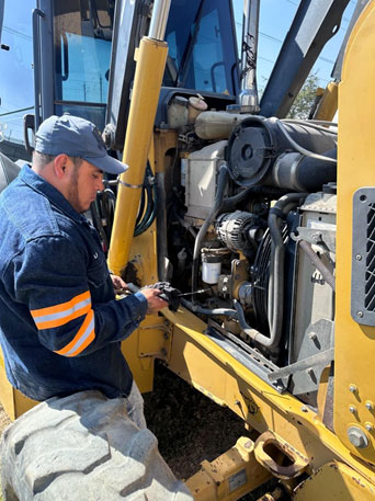Mecánico realizando mentenimioento preventivo a Retroexcavadora CASE